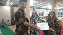Wakil Bupati Solok Selatan, Yulian Efi serahkan dan piagam kepada siswa MDTA Masjid Nurul Ikhlas Kepala Bukit, Adibah Fakhira Jufri.